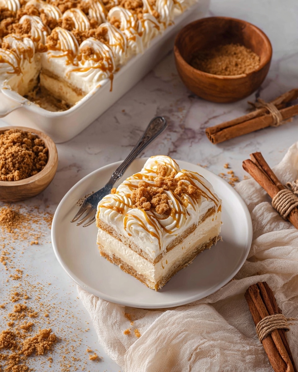 A square piece of layered dessert sits on a white plate with a fork next to it. The dessert has three layers; the base layer is light beige and soft, the middle layer is creamy white, and the top is decorated with swirls of white cream covered with crumbled golden brown bits. Caramel-colored sauce drizzles over the top, adding shine and texture. In the background, there is a larger serving dish with the same dessert, a small wooden bowl filled with more crumbs, and some whole cinnamon sticks tied with twine on a cream cloth. The surface underneath is a white marbled texture. Photo taken with an iphone --ar 4:5 --v 7