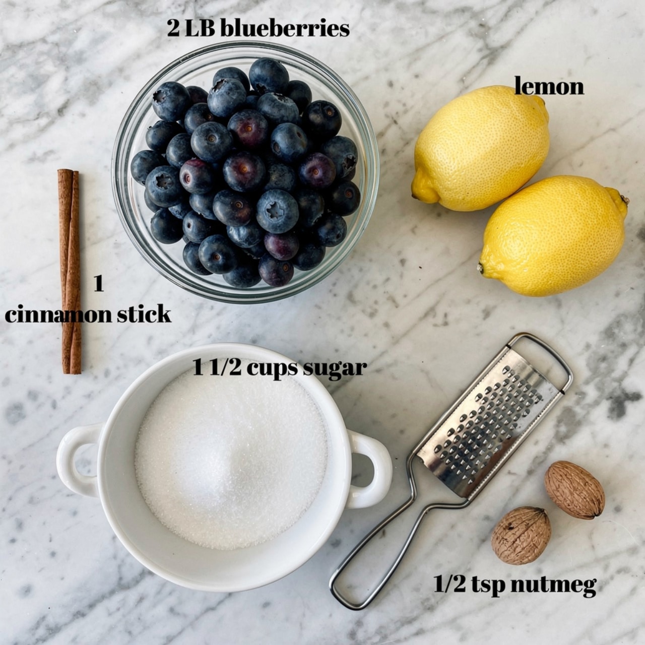 A glass bowl filled with dark blue blueberries sits centered on a white marbled surface, labeled